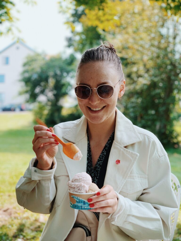 Kvinna med solglasögon äter glass med sked.